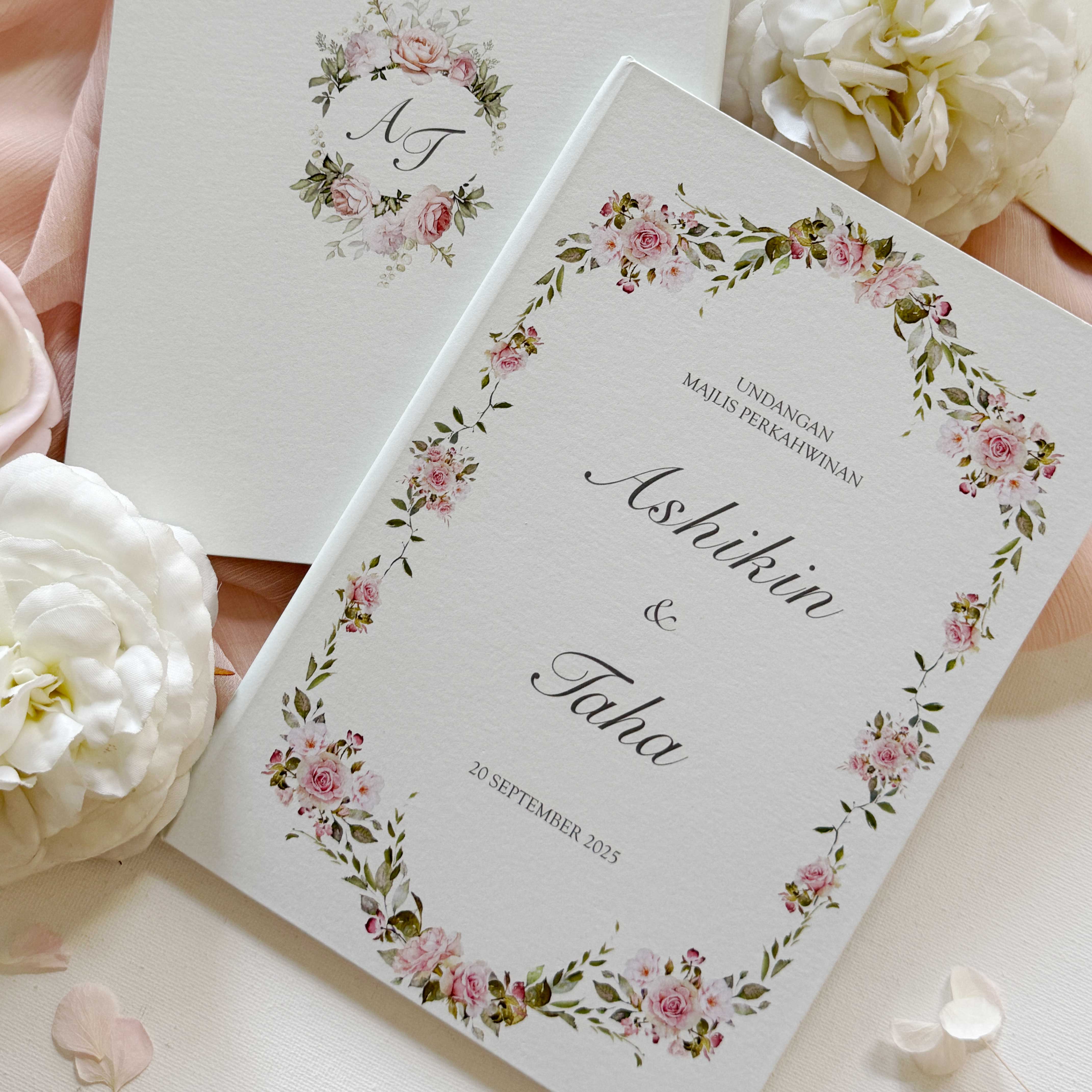 Premium hardcover wedding invitation card with personalized names and date, surrounded by white flowers.