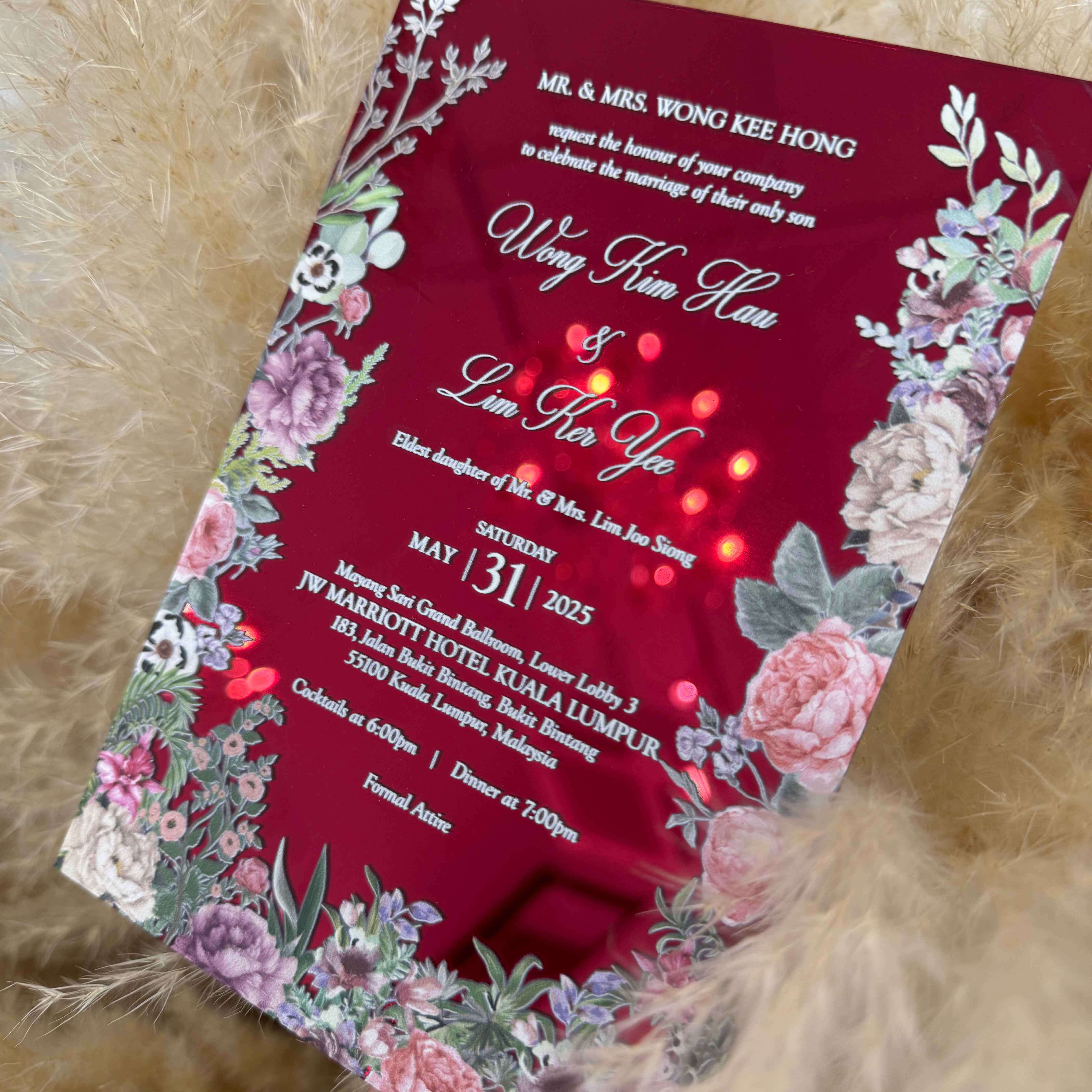 Red acrylic wedding invitation with floral designs on a textured surface