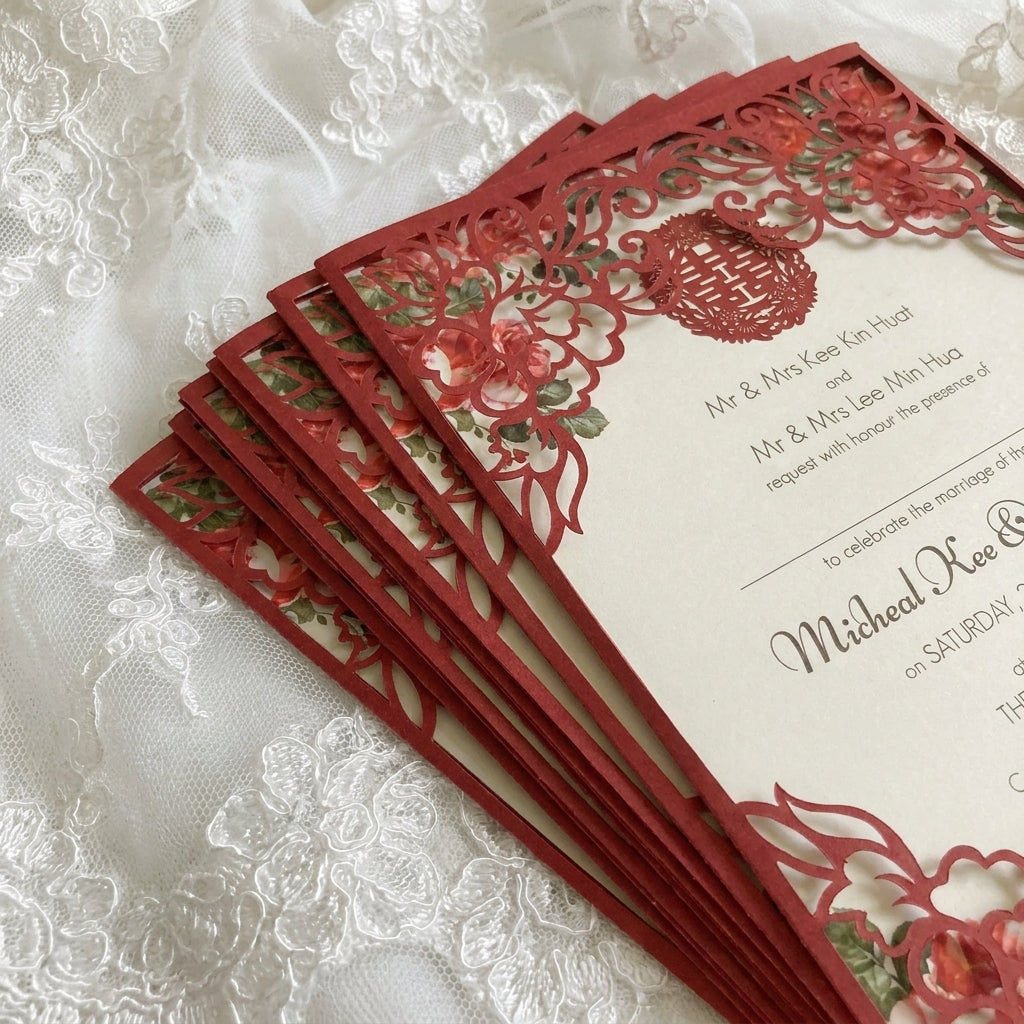 Stack of red laser-cut wedding invitations on a lace background