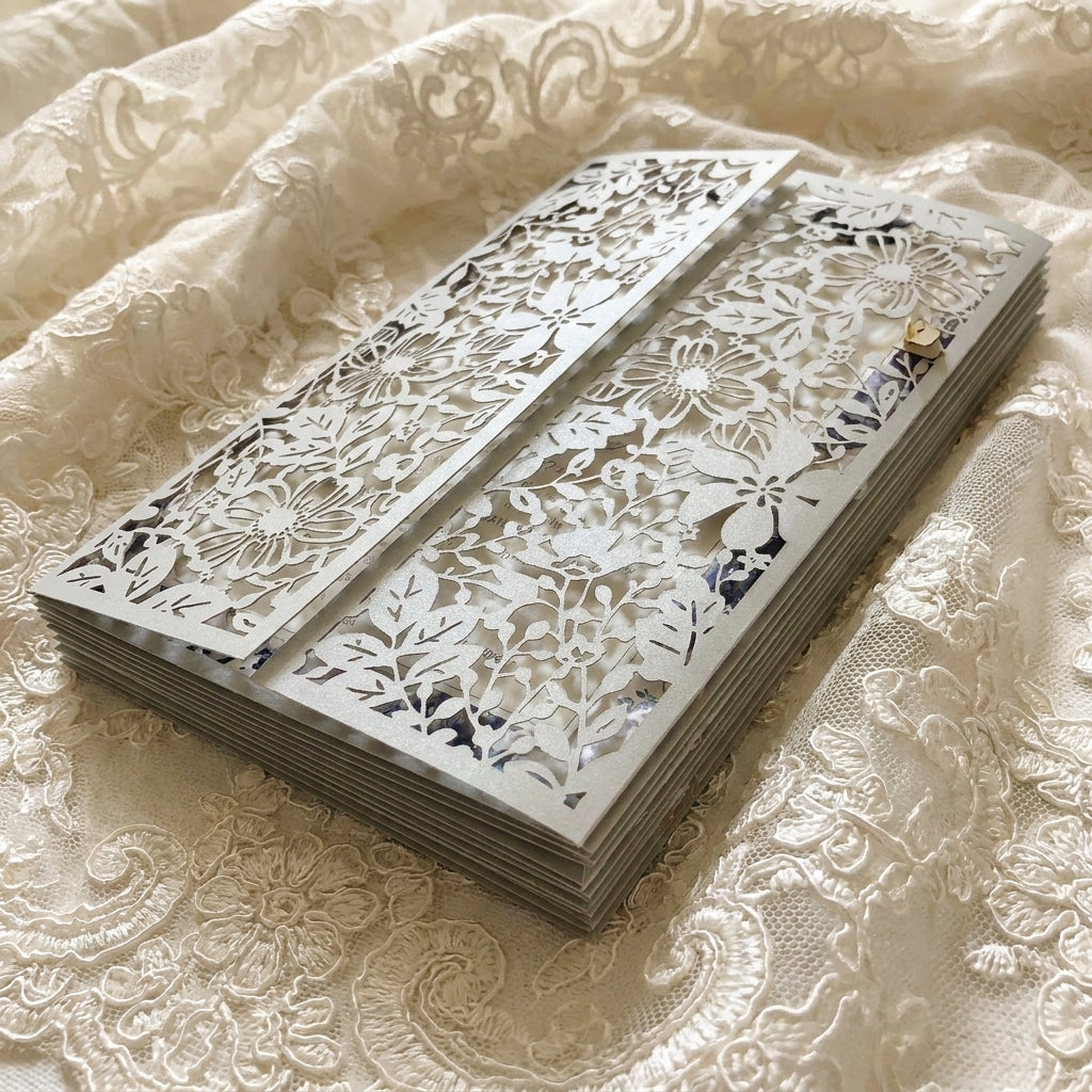 Decorative floral laser-out wedding card design on a lace fabric background