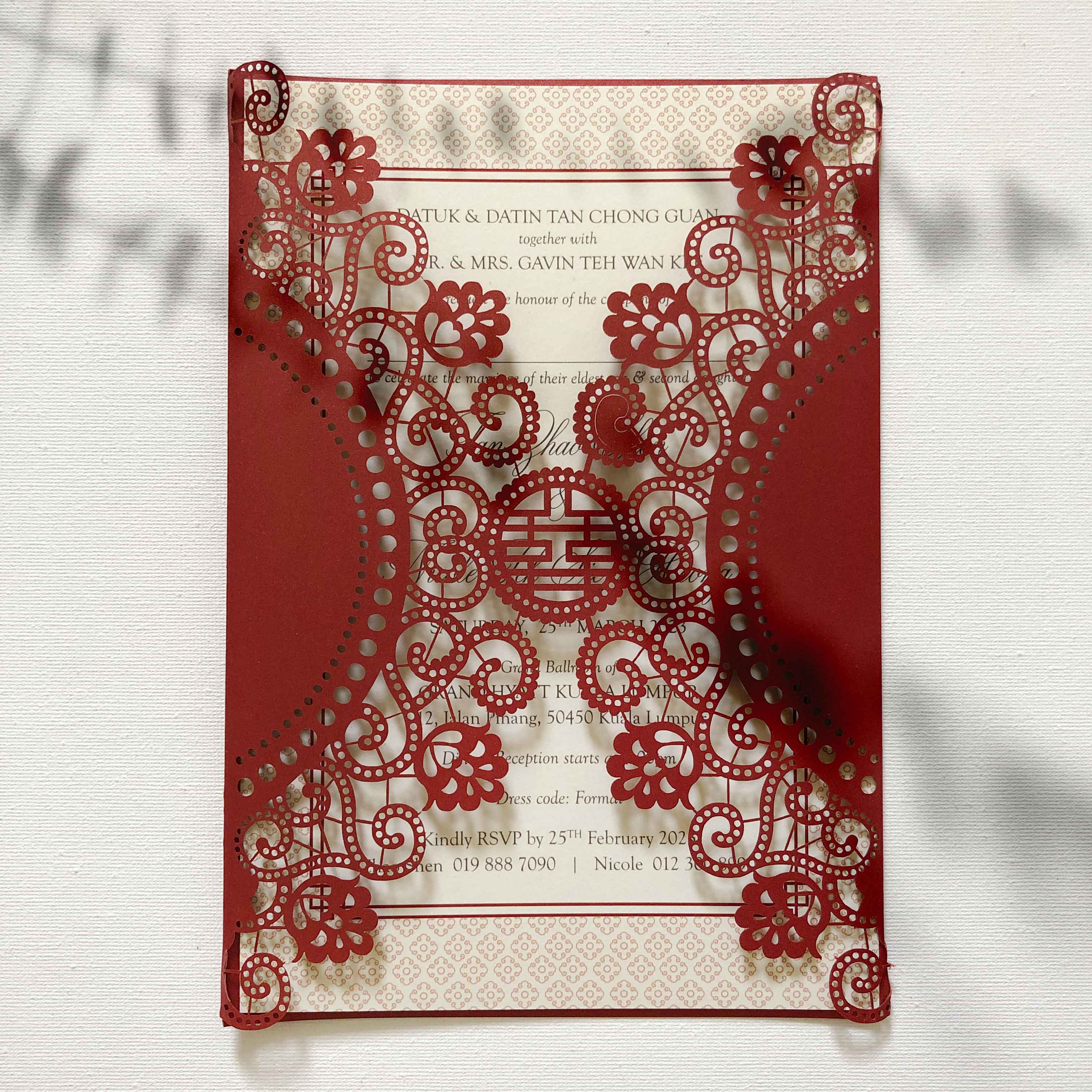 Red and gold laser-cut wedding invitation on a white background