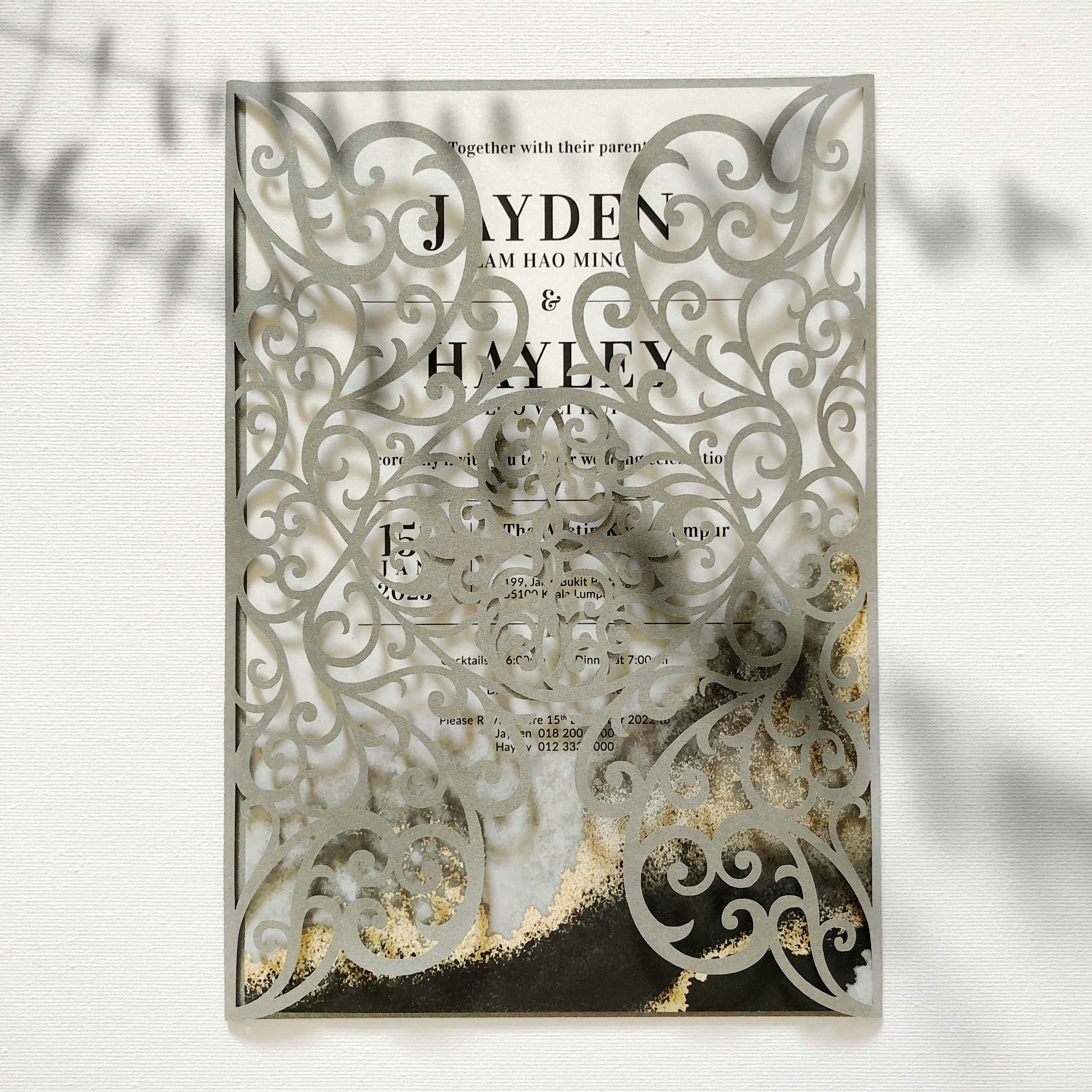 Decorative wedding invitation with intricate cut-out design on a white background