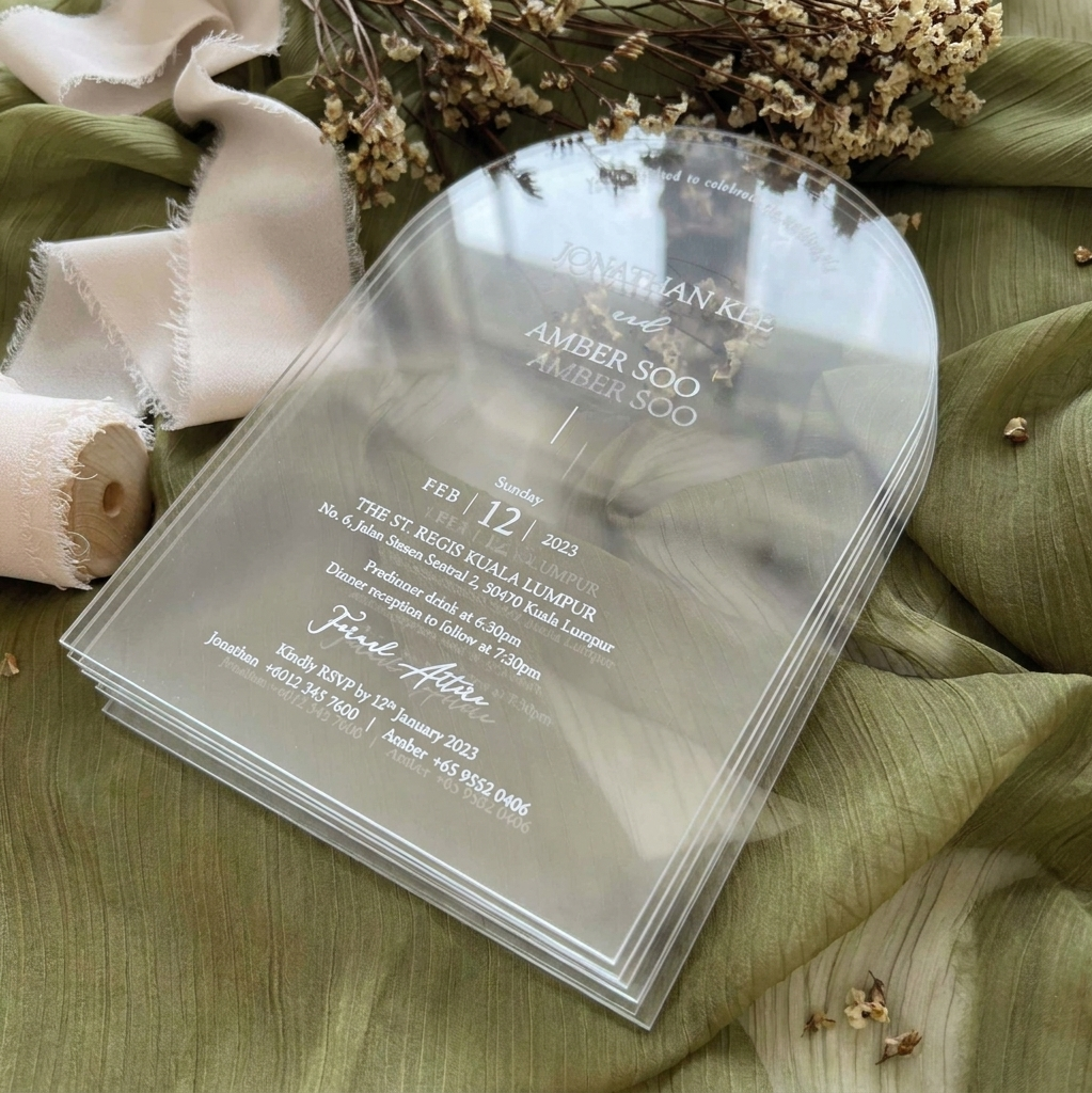 Clear wedding invitations with white text on a green fabric background