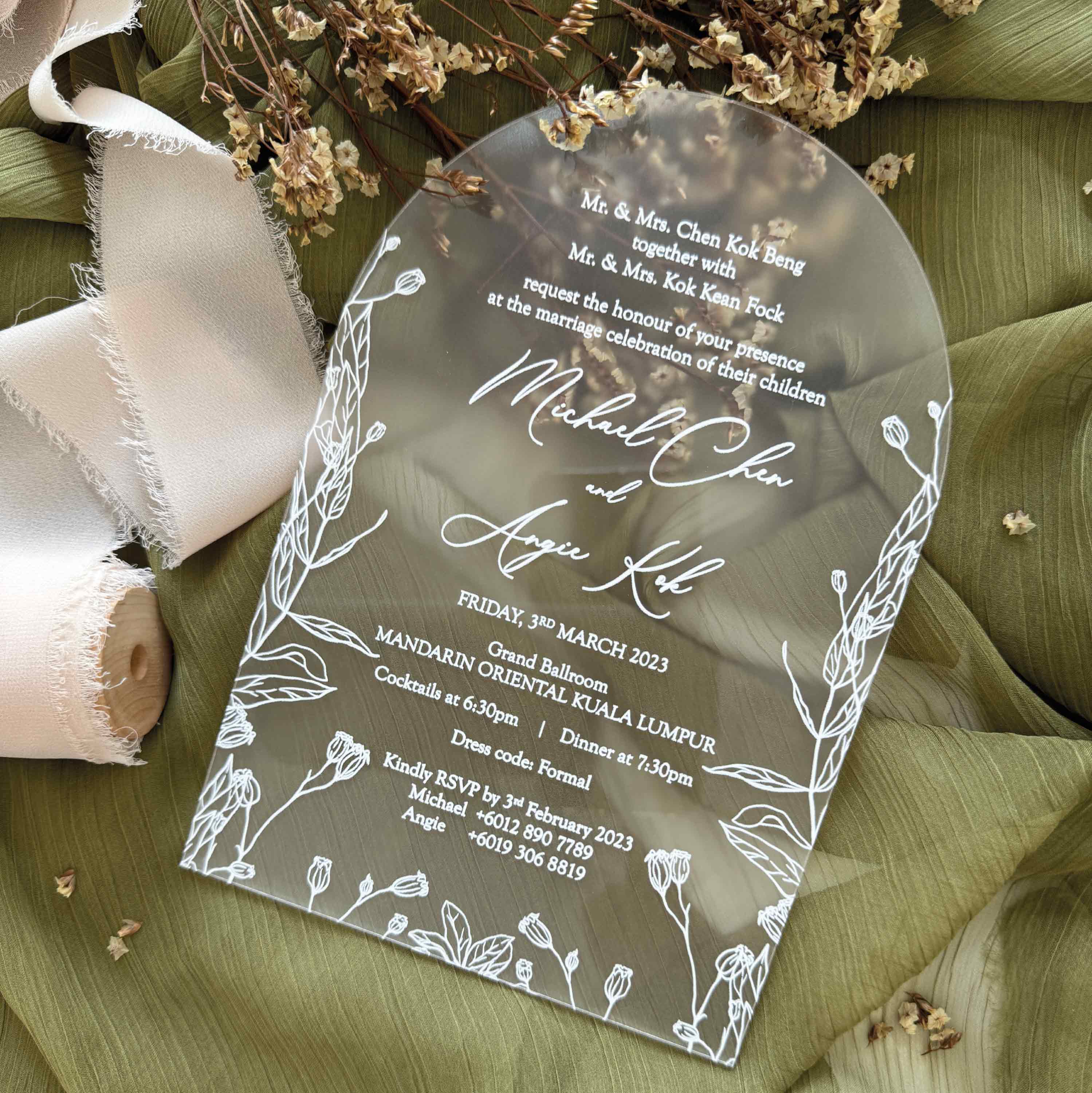 Wedding invitation card with floral design on a green fabric background