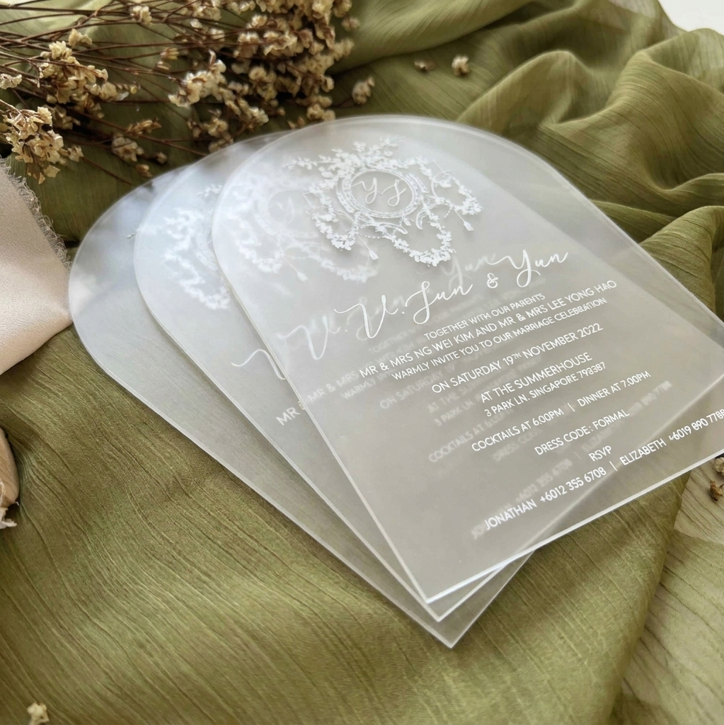 Clear wedding invitations with floral design on a green fabric background