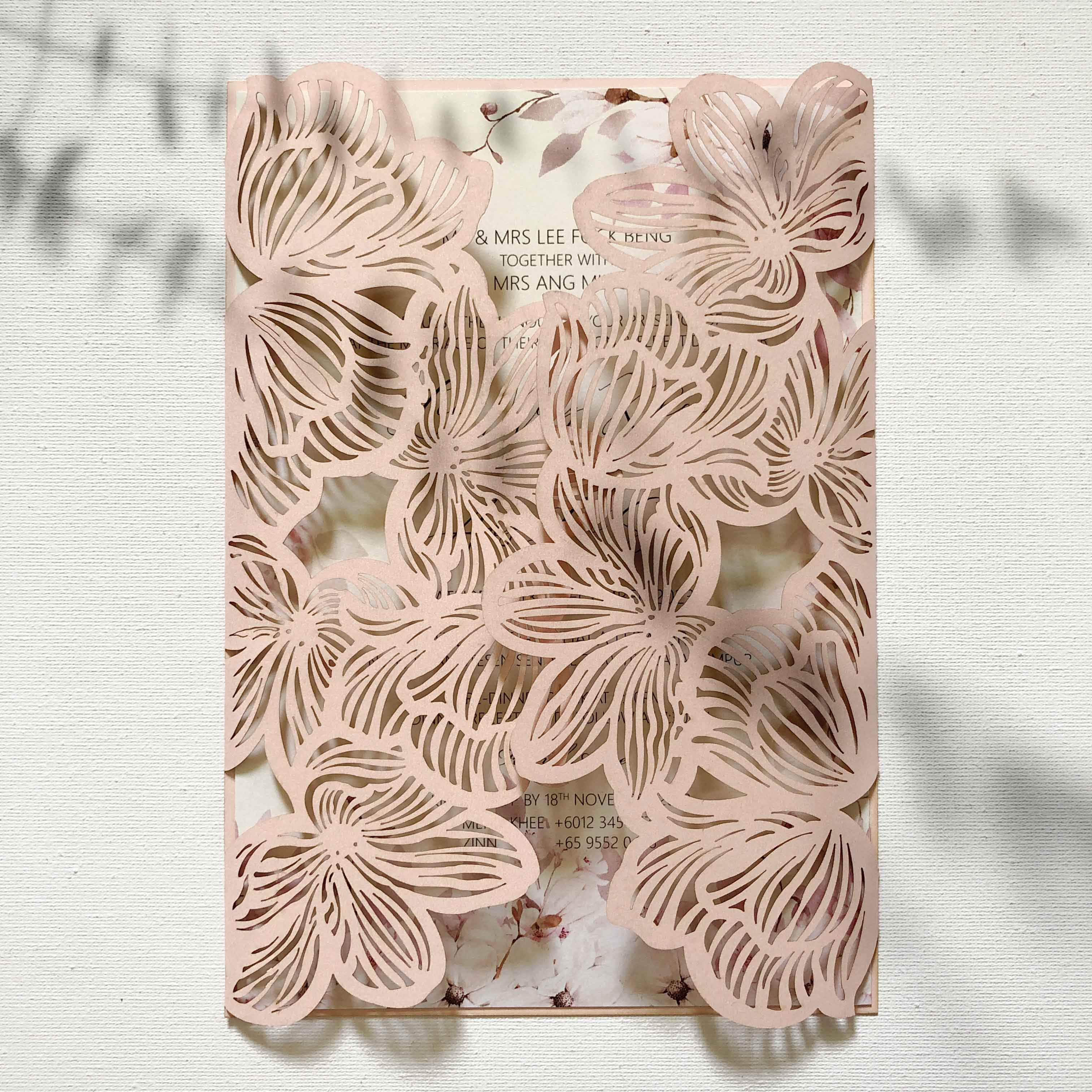 Decorative wedding invitation with floral cutout design on a light background