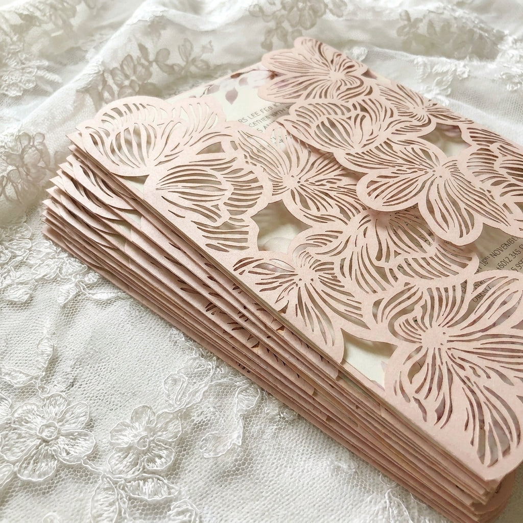 Stack of laser-cut floral paper on a textured white fabric background