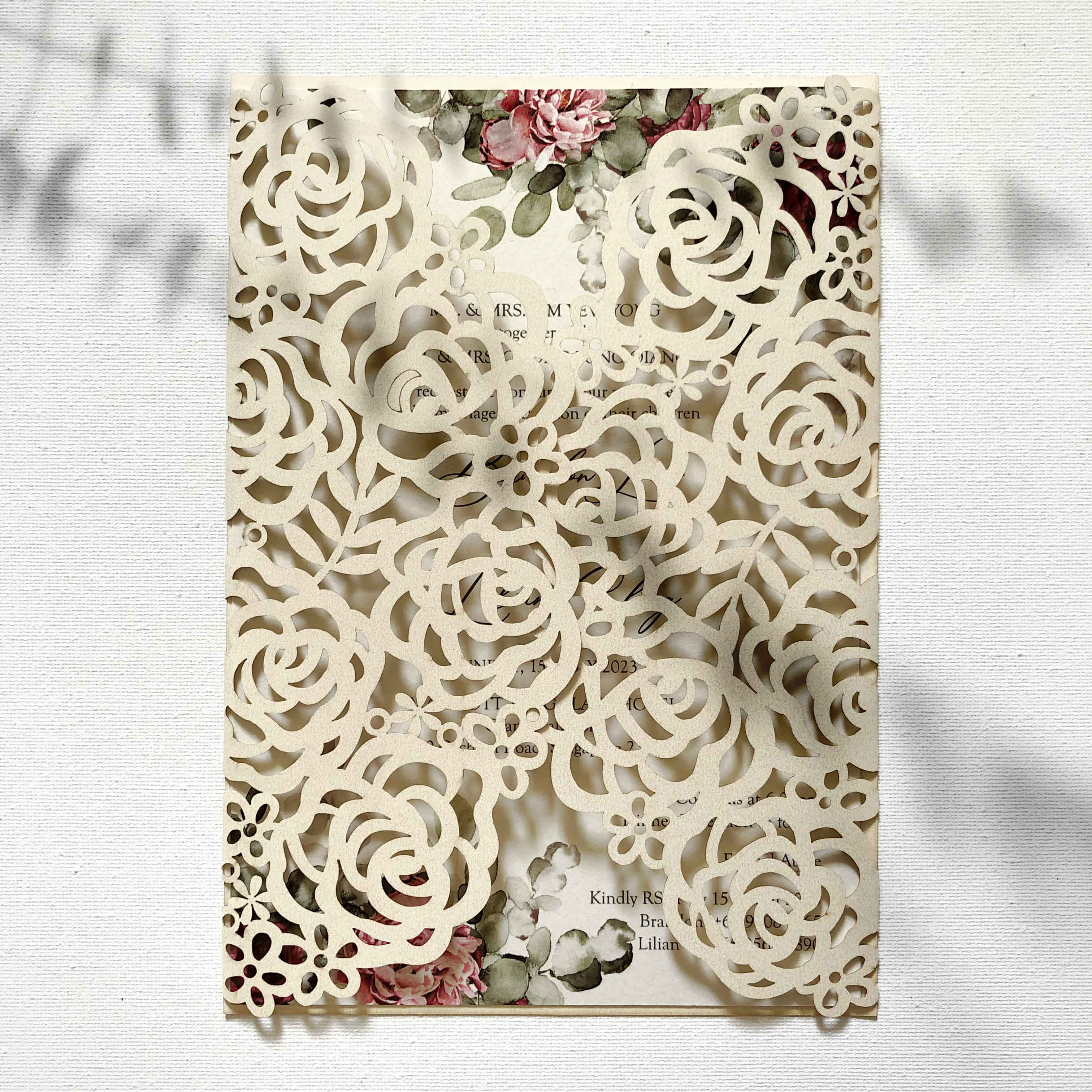 Laser-cut wedding invitation with floral design on a white background