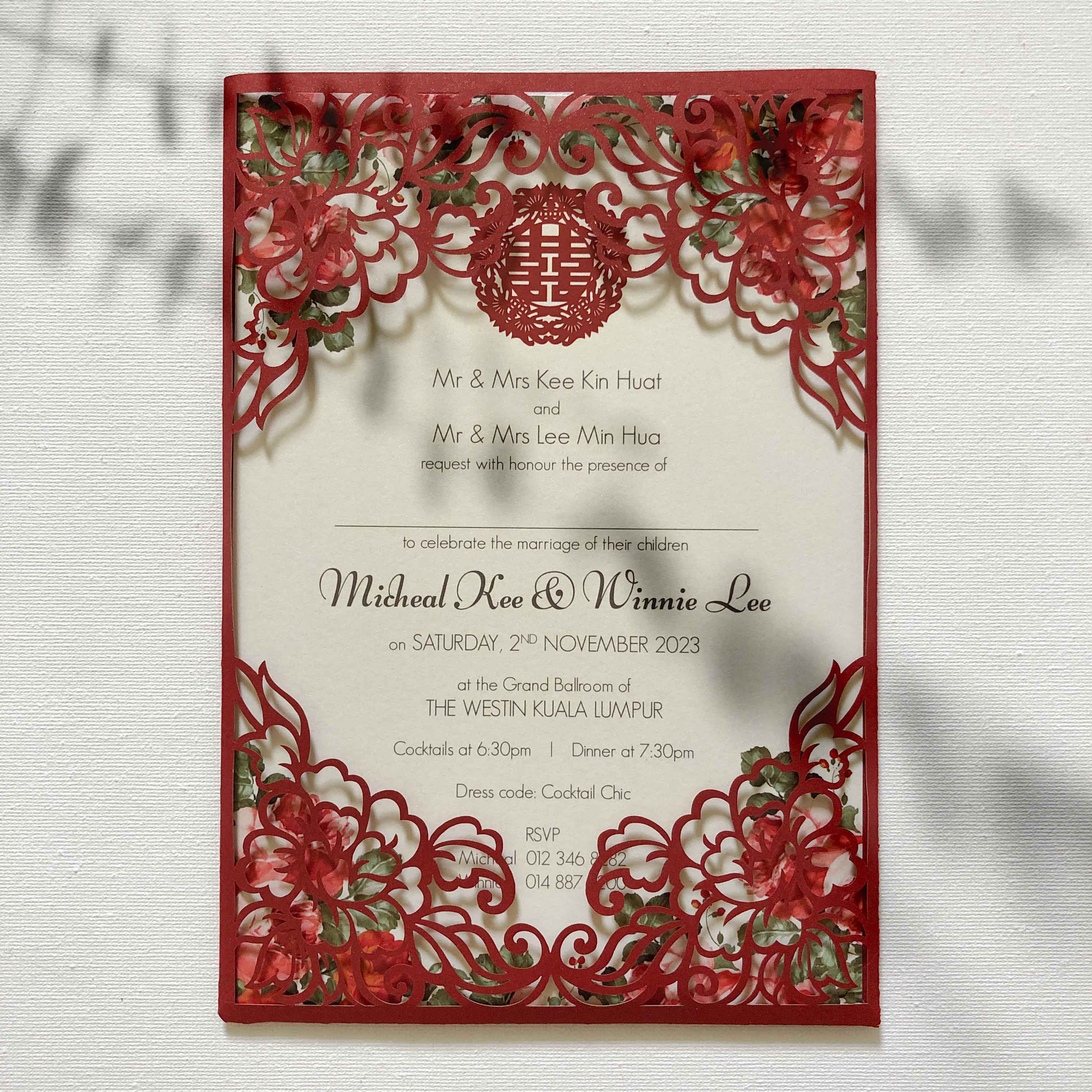 Decorative wedding invitation with red floral designs on a white background