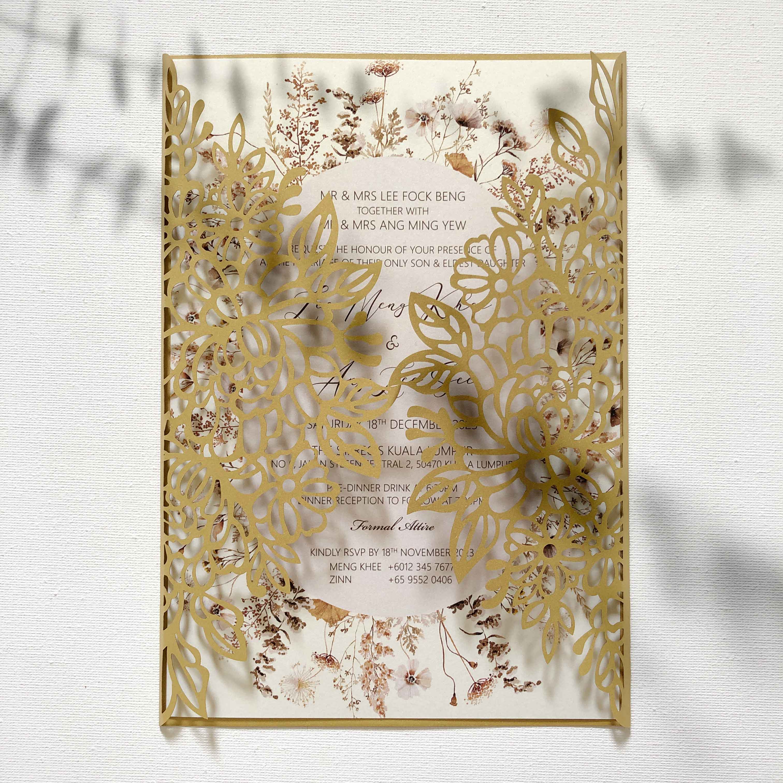 Decorative wedding invitation with gold laser-cut design on a textured white background